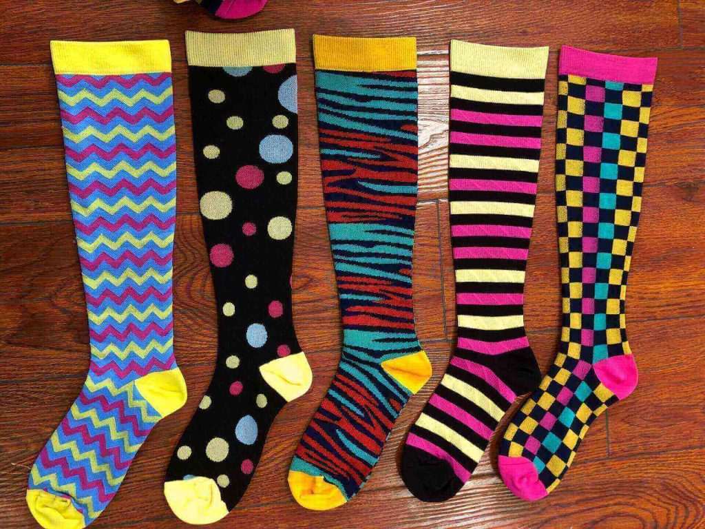 Five pairs of colorful patterned compression socks, including zig-zag, polka dot, and striped designs.