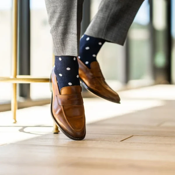Man wearing brown leather penny loafers and navy blue 100 cotton men's dress socks with white polka dots