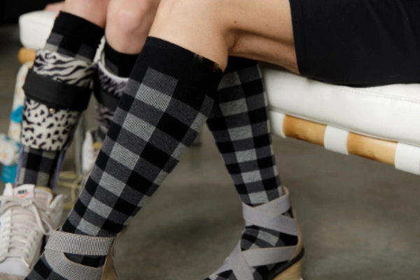 Pair of legs wearing grey and black checkered compression socks
