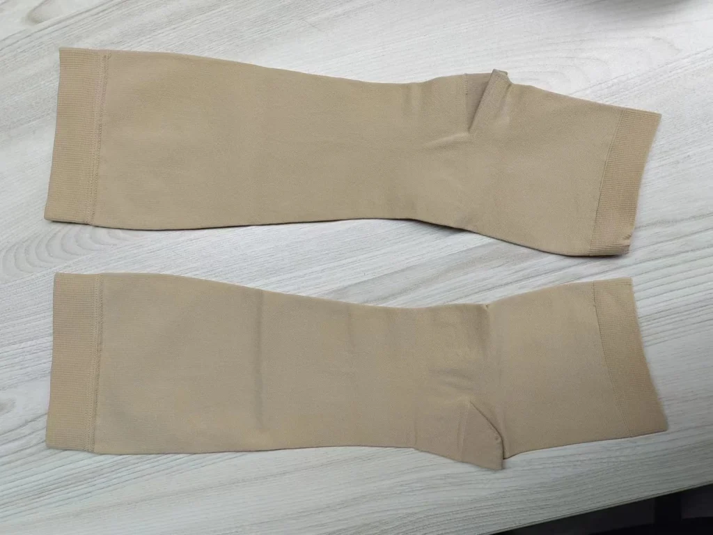 Varicose vein stockings, beige, laid flat on a wooden surface.