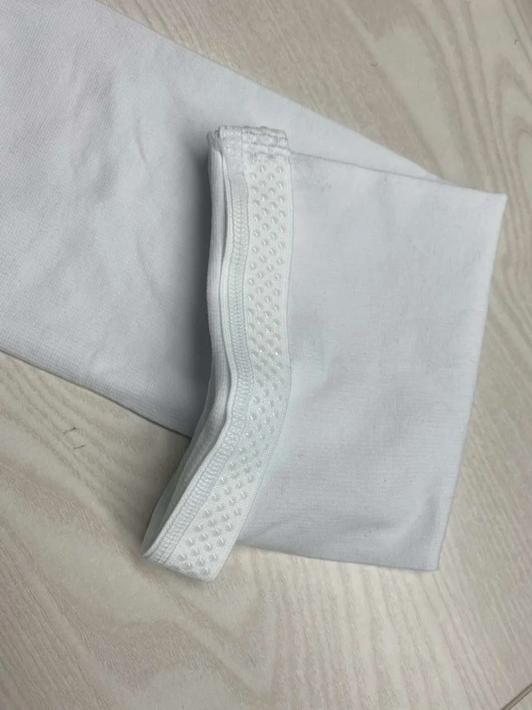 Non-slip cuff medical stocking in light beige, folded.