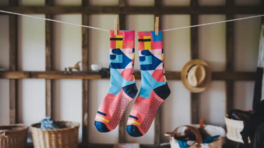 Colorful patterned socks drying on a clothesline in a rustic setting.