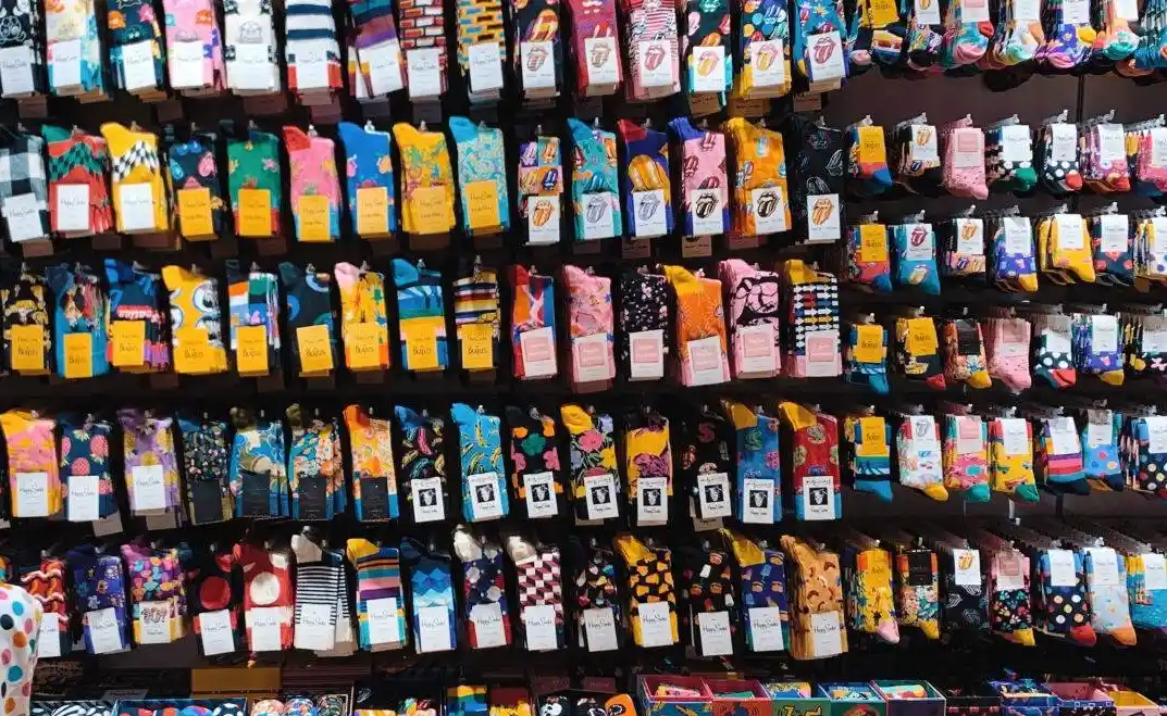 Custom socks in various designs displayed on a wall.