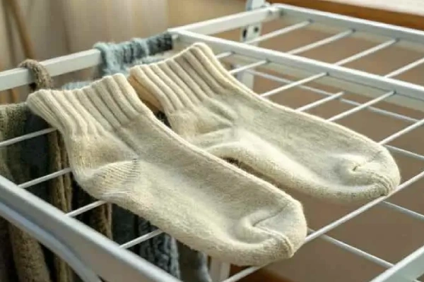 Wool socks laid flat on a towel to air dry naturally by a window