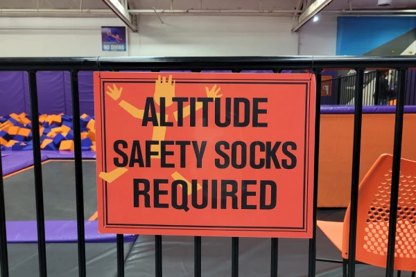 Guest putting on clean grip socks at a park entrance to avoid barefoot contact on shared mats