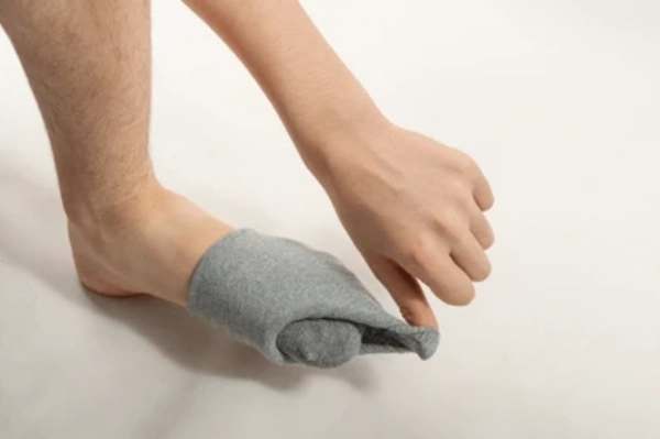Person with swollen red foot from acute gout flare removing compression sock to avoid pressure