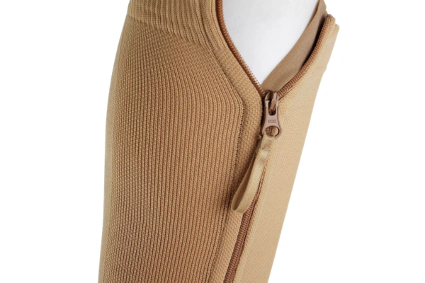 Close up of the elastic top band of a beige zipper compression sock