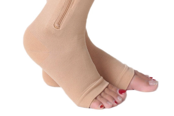Detailed view of the side zipper feature on beige compression stockings
