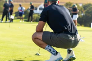 Golfer wearing custom golf socks during a putting stance on the course