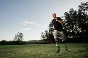 Person with leg prosthesis and stump sock jogging on the grass