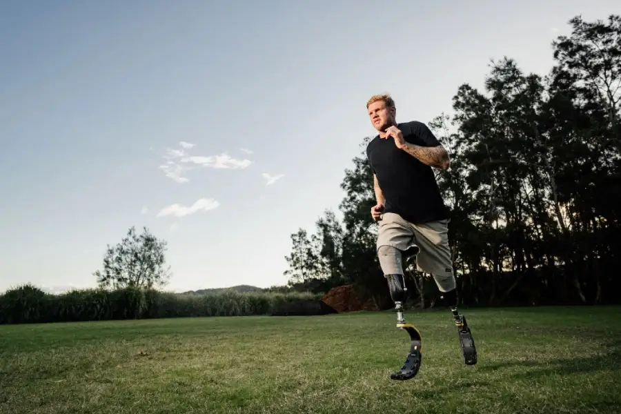 Person with leg prosthesis and stump sock jogging on the grass