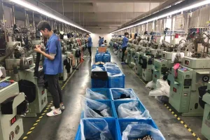 Bulk production facility with workers operating knitting machines for large-scale manufacturing