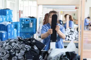 Quality checking process with worker inspecting black compression socks in manufacturing facility