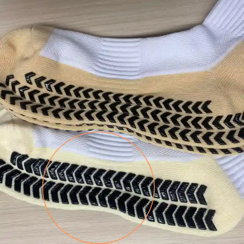 Grip socks sole with uneven herringbone silicone lines circled for quality issue reference