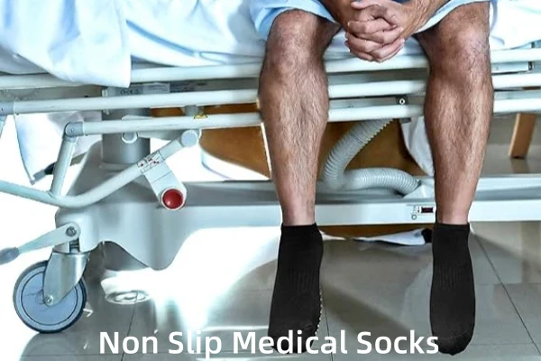 Black anti-slip hospital grip socks for men on a hospital bed.