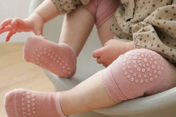 Baby grip socks on infant's feet and knees for crawling.