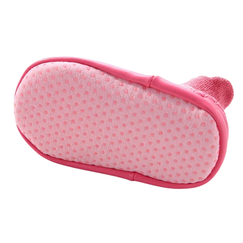 Pink infant shoe-style sock bottom showing dual-texture sole: soft fabric center with durable leather-like perimeter