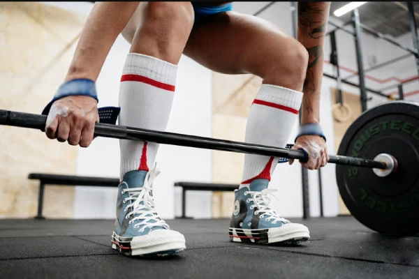 A weightlifter wearing deadlift socks and sneakers prepares for a deadlift.