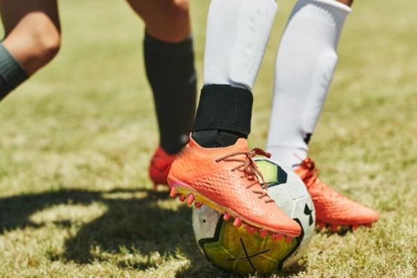 Players wearing soccer shin pads and socks on a soccer ball during a game