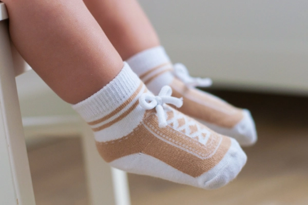 Infant socks designed like shoes with laces on baby's feet.