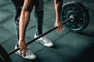 A person wearing powerlifting socks and athletic shoes grips a barbell for a deadlift.