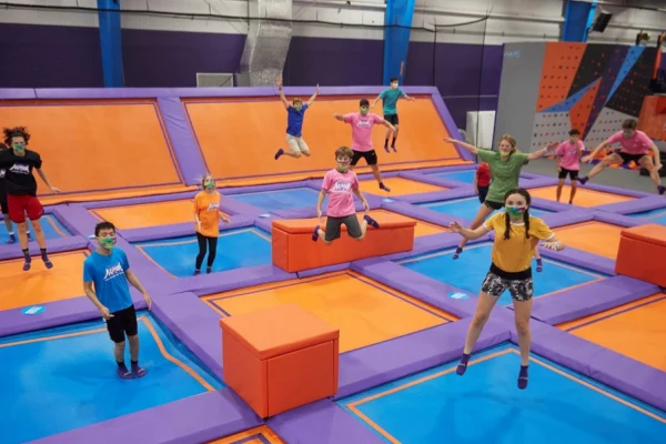 Trampoline socks for kids are worn by a group of young people jumping together.