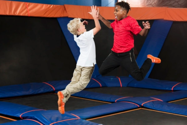 Trampoline socks for kids are worn by a group of young people jumping together.