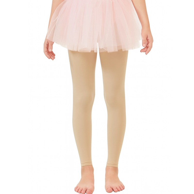 A pair of beige kids footless tights are shown worn on a child for dance.