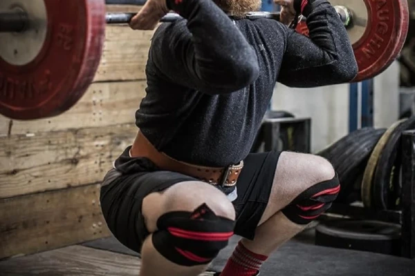 Weightlifter squatting while wearing neoprene knee sleeves for joint support