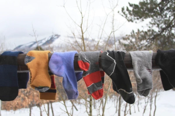 Washed ski and snowboard socks drying on a railing outdoors.