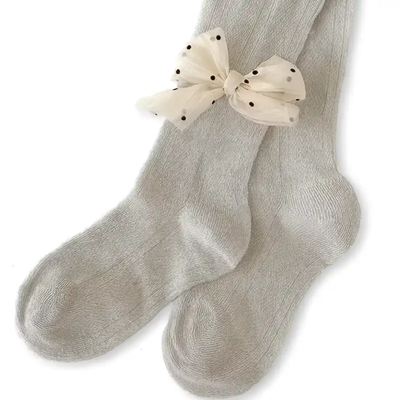 Pale gray kids' tights with a spotted white reinforced bow trim on the ankle