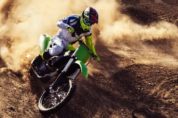 Motocross rider deflecting roost on shin with padded motocross socks under boot tongue