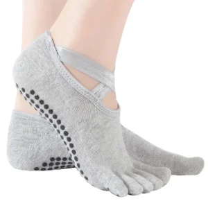 Close-up of gray yoga toe socks with criss-cross straps and black non-slip grips on the sole