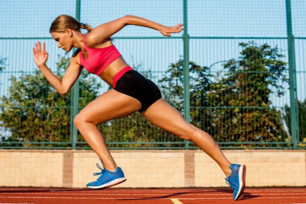 Female athlete sprinting on track wearing Active Sports no show socks for performance support