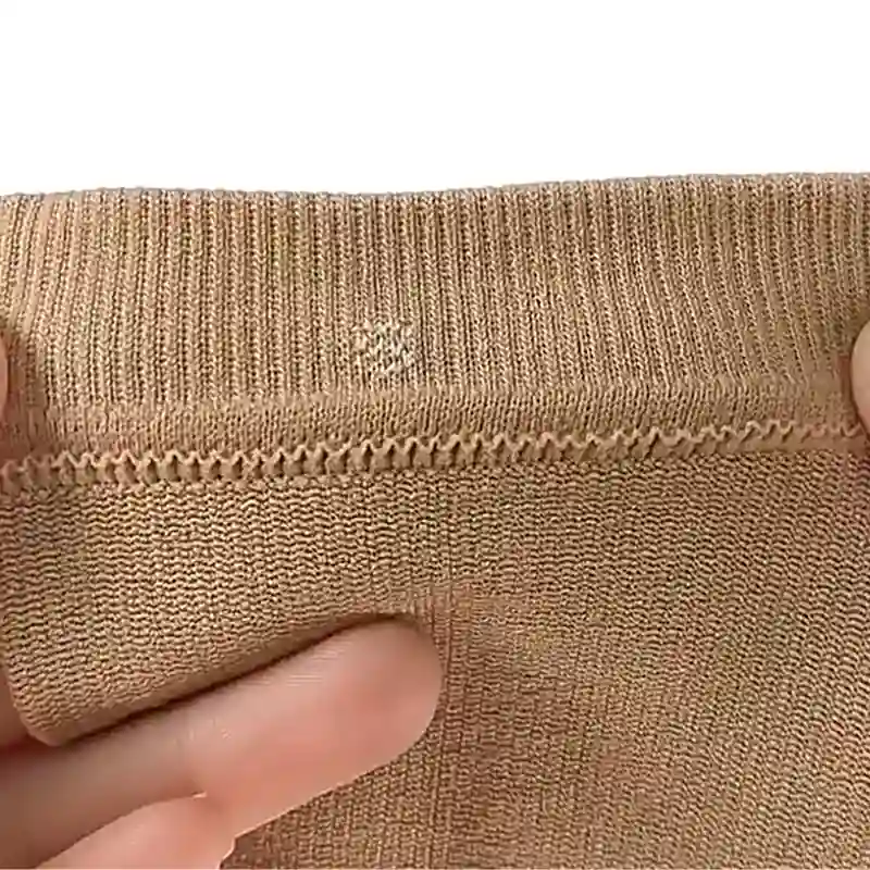 Close up of a beige calf compression sleeve showing durable double reinforced stitching along the cuff