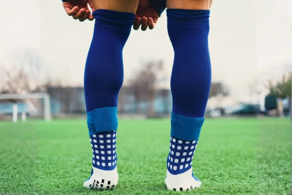 Grip socks worn by a soccer player standing on a green grass field