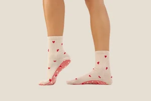 Grip socks with heart pattern worn during standing side profile view