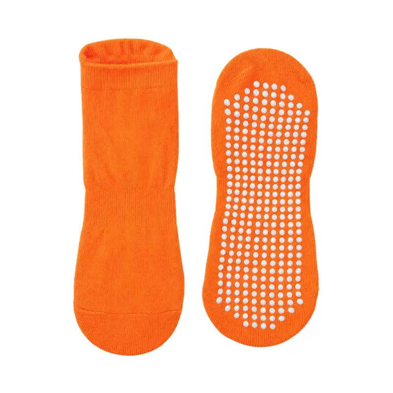 Pair of orange non-slip grip socks with white rubber dots on the sole