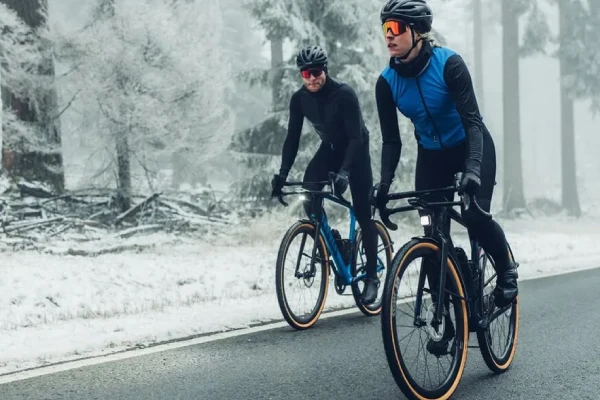 Two cyclists riding on a frosty winter road wearing thermal winter cycling socks