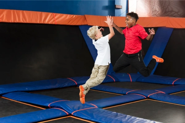 Kids jumping on an indoor trampoline park wearing orange non-slip grip socks