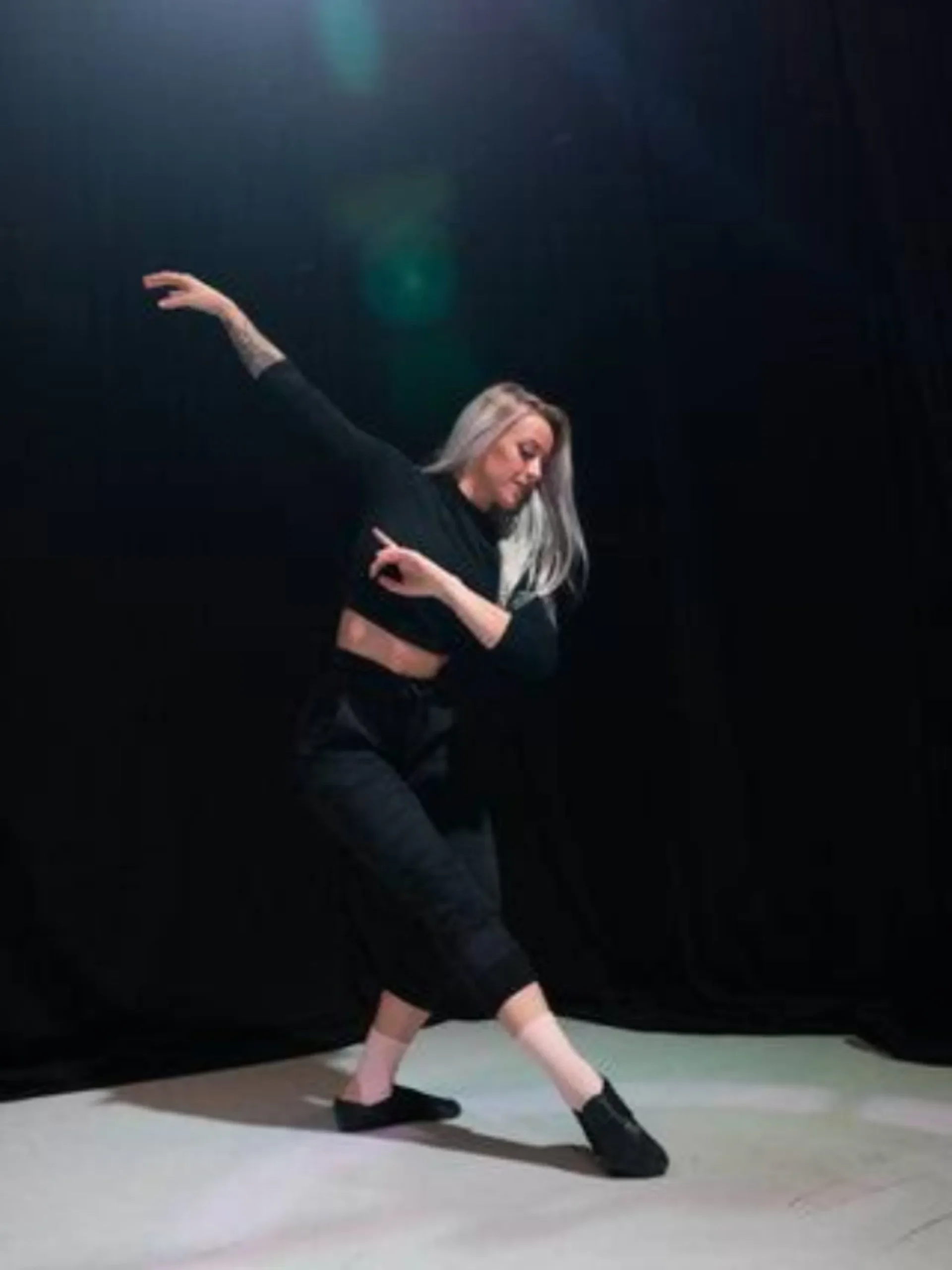 Female modern dancer wearing black dancewear and performing on stage