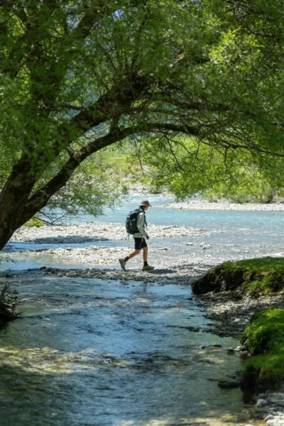 Hiker crossing a shallow river bed wearing protective waterproof hiking socks and shoes