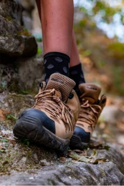 Mid hiking boots paired with cushioned crew socks on a rocky trail