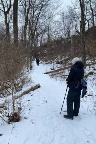 Trekker hiking along a snowy winter trail wearing warm heavyweight hiking socks and boots