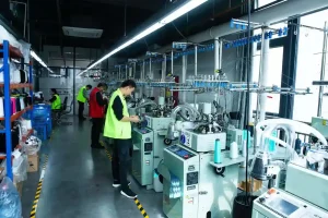 Sock factory production floor with circular knitting machines and workers
